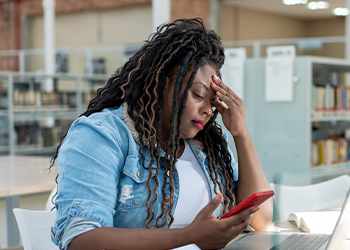 A woman looking down on her phone with a look of concern.