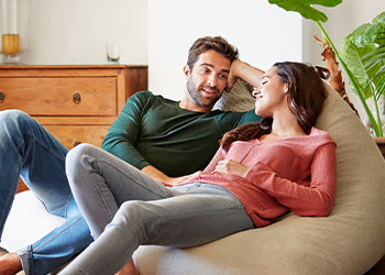 Two people sitting on a bean bag inside their house