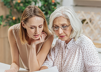 A woman and her mother look down at some paperwork