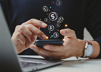 Someone holding a smart phone, with illustrated coins floating out of the phone.