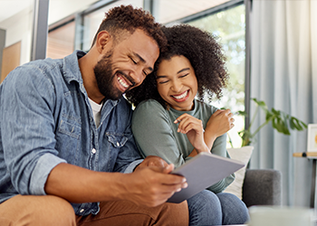 Two people hugging and smiling at a tablet