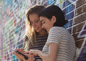 Two people looking down at a cell phone