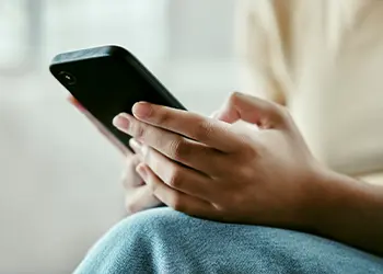 A close-up of hands holding a mobile phone
