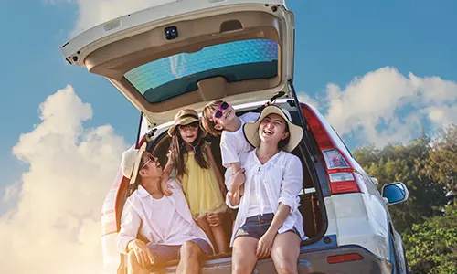 Family sitting on the floor of the trunk of their new car