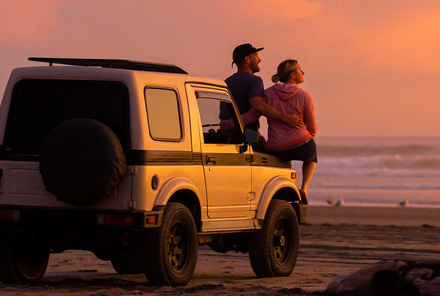 Car on beach at sunset