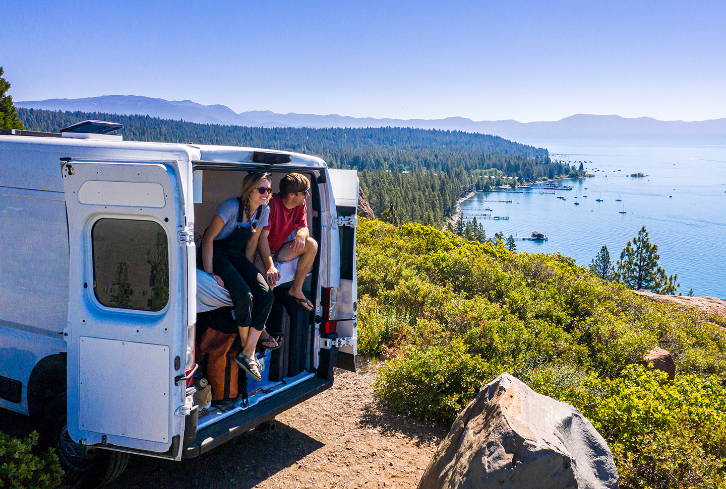 A couple enjoying their RV on a lakeside cliff