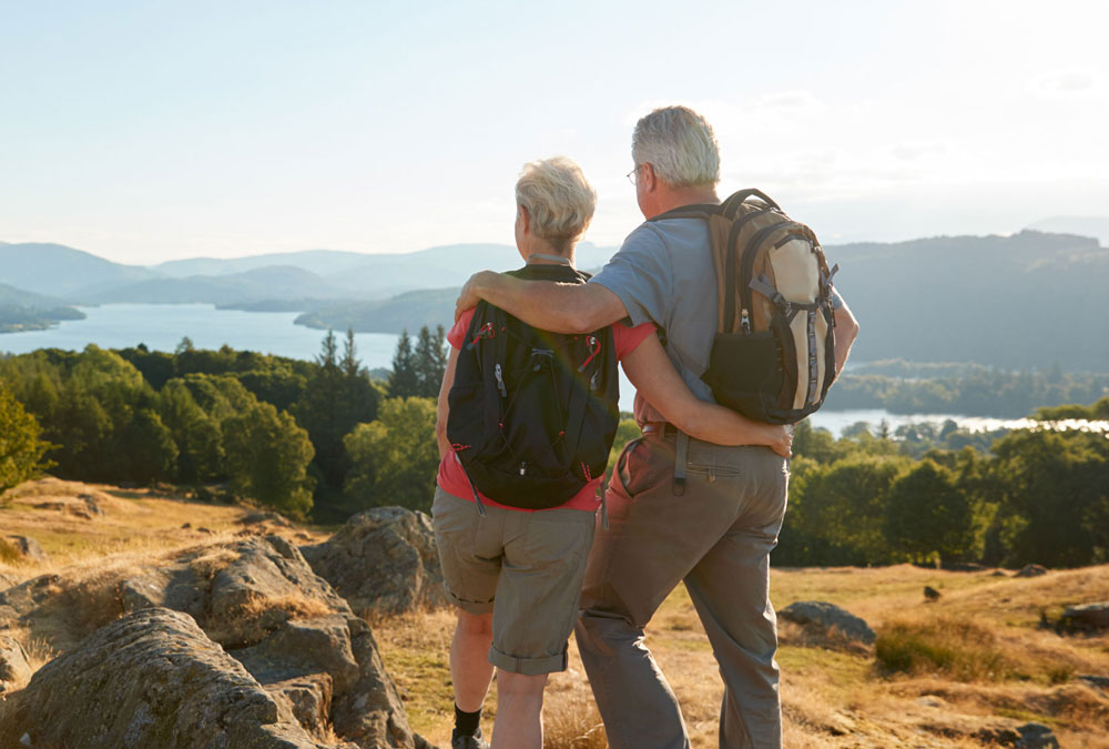 Two hikers stand looking at a mountainous view